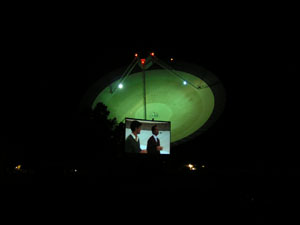 Two men appear on the dish surface on the movie screen with the telescope in the background