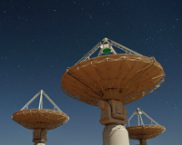 A ground view of three ASKAP antennas against a starry sky.