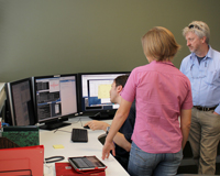 Three people standing around a computer in the Science Operations Centre (SOC).