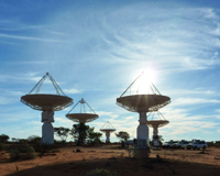 Five ASKAP antennas standing at the MRO under a sunny sky.