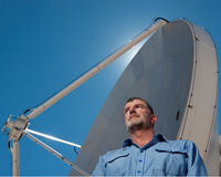 Dr Lewis Ball standing in the foreground of a radio telescope dish. Photo credit: ALMA(ESO/NAOJ/NRAO), M. Alexander (ESO).