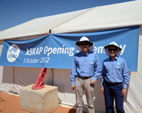 Two men (Max Voronkov and Juan Carlos Guzman) wearing blue CSIRO shirts standing in front of a marquee decorated with a blue banner that says 'ASKAP Opening Ceremony, 5 October 2012'.
