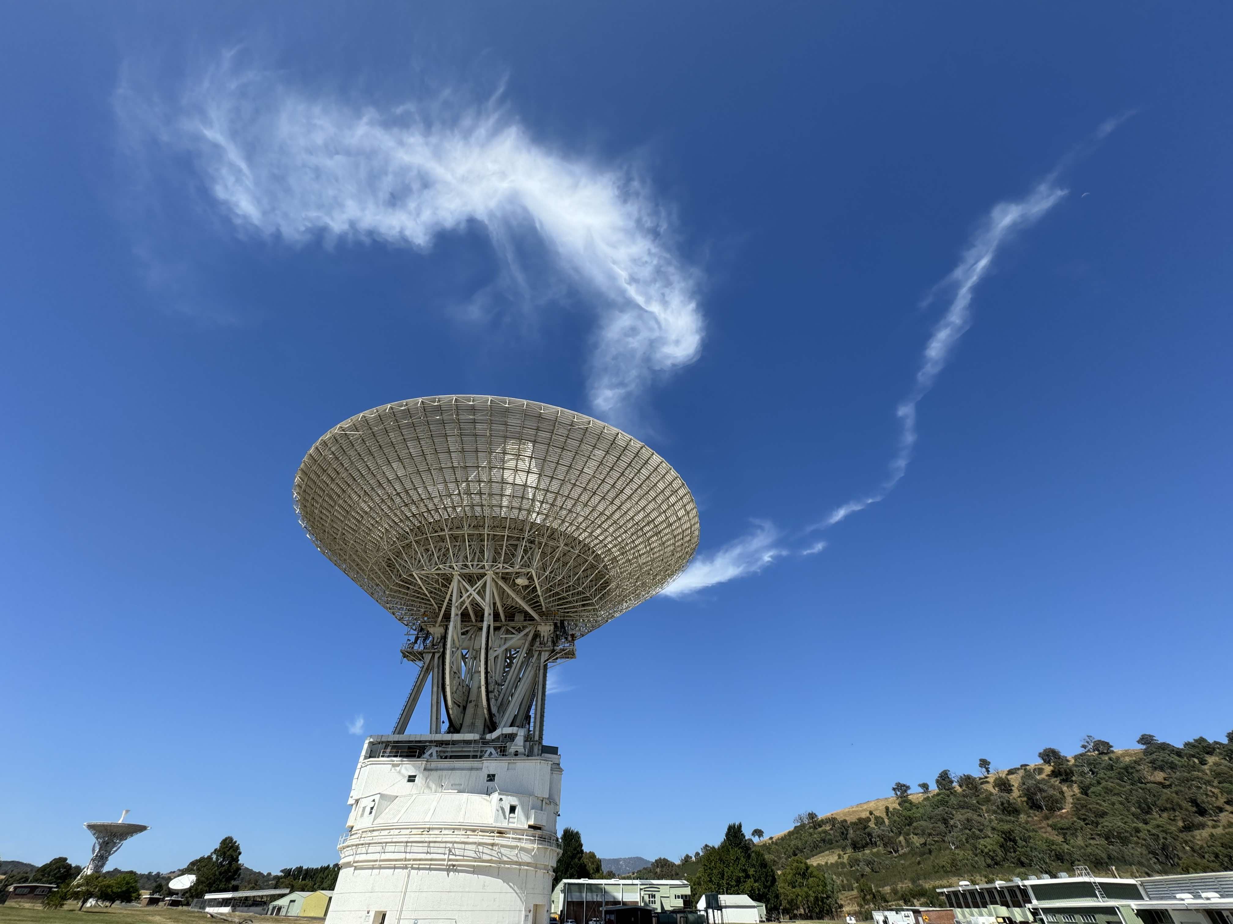 The 70m DSS-43 antenna of the Canberra Deep Space Communication Complex with wisps of cloud in the background.